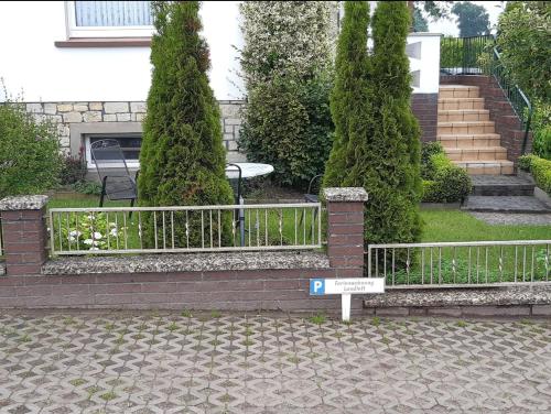 a fence in front of a house with trees at Ferienwohnung Landluft in Ostercappeln