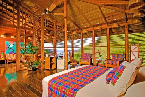 Anse Chastanet Resort في سوفريير: غرفة نوم بسرير وكراسي في غرفة