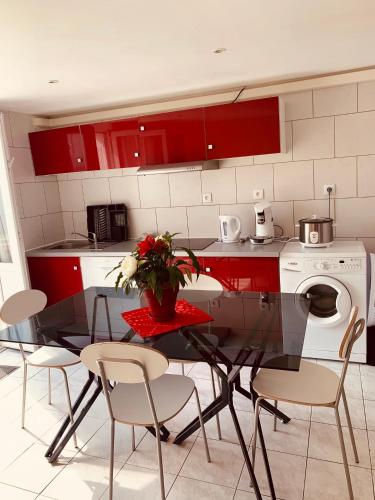 une cuisine avec des placards rouges et une table avec des chaises dans l'établissement Belle Maison avec jardin RDC T3 de 70m2 Vacances ou cure thermale Rochefort, à Rochefort