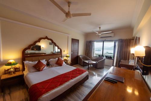 ein Hotelzimmer mit einem Bett und einem Wohnzimmer in der Unterkunft Hotel Hilltop Palace in Udaipur