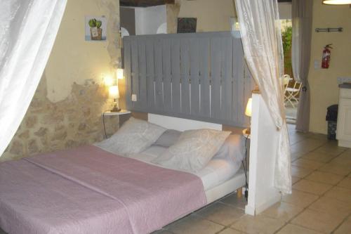 a bedroom with a bed with a gray headboard at La Bergerie Lou Mas Li Pitchoun in Gordes