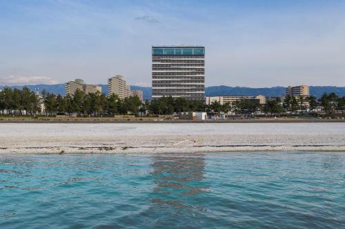 a view of a beach with a tall building in the background at Hotel Bay Gulls in Tajiri