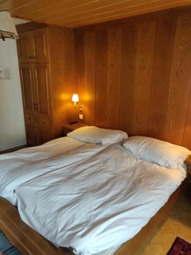 a bed with white sheets and pillows in a room at Pension Eder - Joker card included in summer in Saalbach Hinterglemm