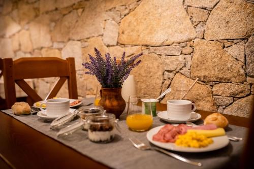a table with breakfast food and a stone wall at Quinta das Oliveiras Turismo Rural in Fundão