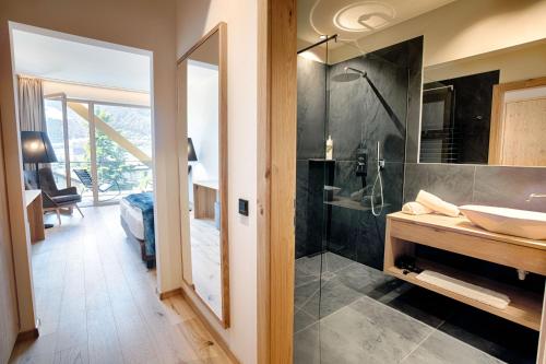 a bathroom with a walk in shower and a sink at Genusshotel Diamant in Naturno