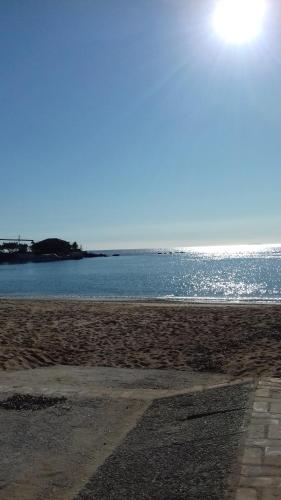 a beach with the sun shining on the water at iliolithos rooms in Kardamili
