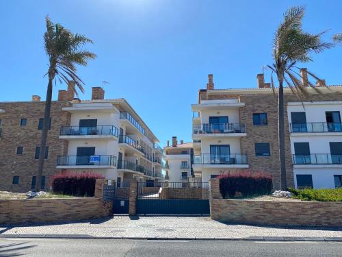 a row of apartment buildings with palm trees in front at High quality T2 apartment In SMP in São Martinho do Porto