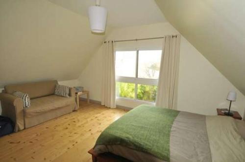 ein Schlafzimmer mit einem Bett, einem Sofa und einem Fenster in der Unterkunft Un Jardin en Pente Douce in Locquénolé