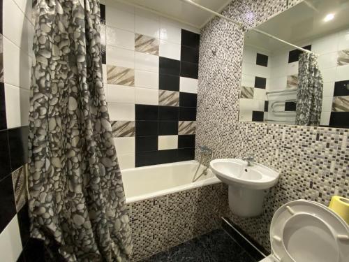ein Badezimmer mit einem Waschbecken, einer Badewanne und einem Duschvorhang in der Unterkunft Comfy Apartment Most City Area in Dnipro