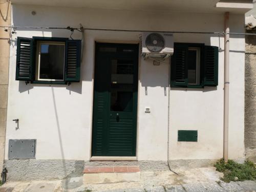una porta verde e due finestre su un edificio di Casa Vacanze "A Machina Ro Ghiaccio" a Noto