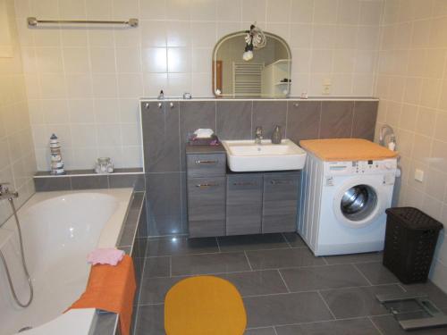 a bathroom with a tub sink and a washing machine at Ferienwohnung Sonja Sinsheim in Sinsheim