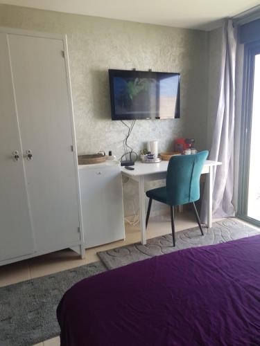 een slaapkamer met een bureau, een stoel en een televisie bij Chambre chez Ikrame in Malemort-du-Comtat