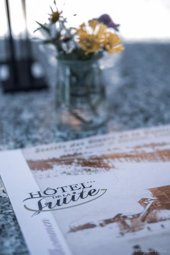 a table with a vase with flowers and a napkin at HOTEL de la Truite & SPA Le petit Nautilus in Le Pont