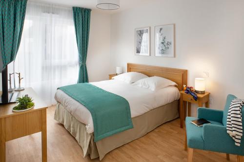 - une chambre avec un grand lit et une chaise bleue dans l'établissement Domitys - Galilée, à Cergy