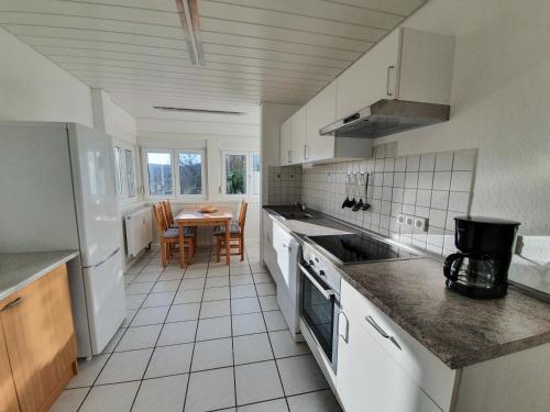 a kitchen with white appliances and a table with chairs at Ferienwohnung Schwarzwaldblick in Unterreichenbach