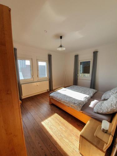 a bedroom with a large bed and two windows at Ferienwohnung Schwarzwaldblick in Unterreichenbach