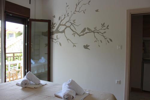 a bedroom with a bed with towels and birds on the wall at House Ekton in Pefkari