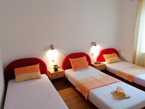 Stolac的住宿－Apartmani Stolac，带红色椅子的客房内的三张床