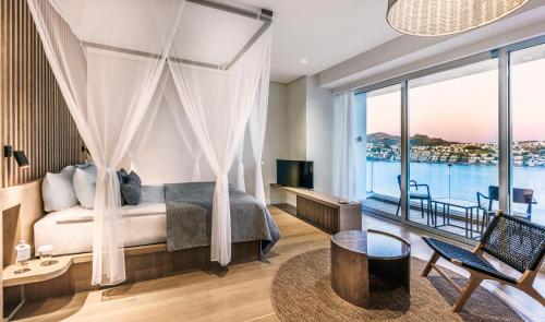 a bedroom with a bed and a large window at Cape Bodrum Luxury Hotel & Beach in Gundogan