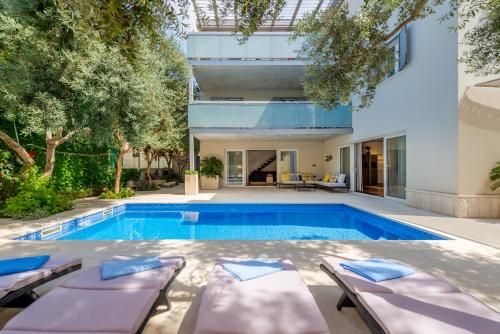 a swimming pool in the backyard of a house with two lounge chairs and a house at Apartment Rex Exclusive in Split