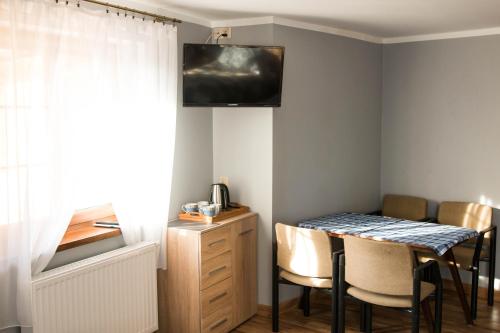 Habitación con mesa con sillas y TV en la pared. en Agroturystyka Szalejów 117 en Szalejów Górny