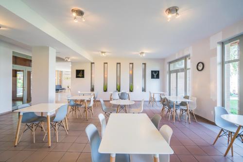 una cafetería con mesas, sillas y ventanas en Holiday Hotel Siófok en Siófok