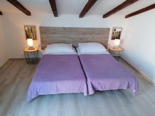 a bedroom with two beds with purple sheets and two lamps at Apartments Crikvenica in Crikvenica