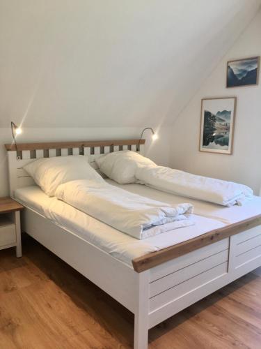 a white bed with a wooden frame in a room at Ferienwohnungen Familie Mapenzi in Waischenfeld