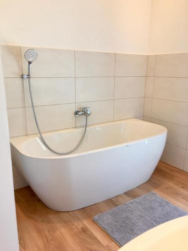 a white bath tub with a shower in a bathroom at Ferienwohnungen Familie Mapenzi in Waischenfeld