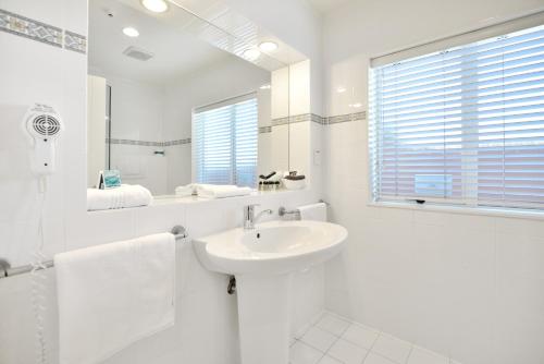 a white bathroom with a sink and a mirror at Shoreline Motel in Napier