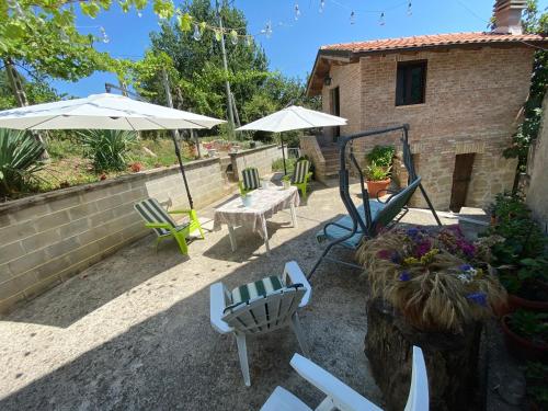a patio with chairs and umbrellas in front of a house at Casa Vacanze Gli Allori in Venarotta