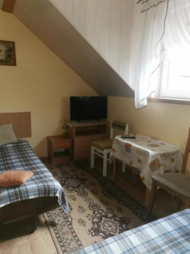 Pokój z 2 łóżkami, stołem i telewizorem w obiekcie Czerwonki Apartament w mieście Mrągowo