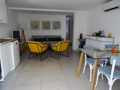a kitchen and dining room with yellow chairs and a table at LUVA d'Azur, Rez de villa LE RIOU - LE VALLON in Le Bar-sur-Loup
