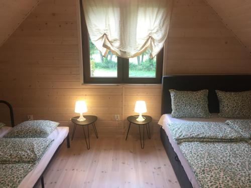 two beds in a room with two lamps on tables at LEŚNE RANCZO AGROTURYSTYKA in Międzychód