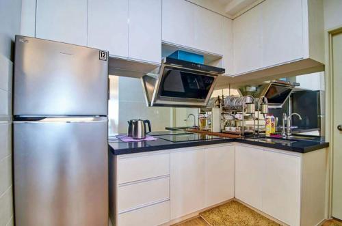 a stainless steel refrigerator in a kitchen with white cabinets at Sekinchan PaddyView Homestay in Sekincan