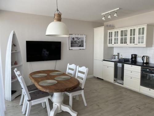 a kitchen with a wooden table and white cabinets at Apartamenty AMALIA in Rewal