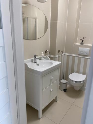 a white bathroom with a sink and a toilet at Apartamenty AMALIA in Rewal