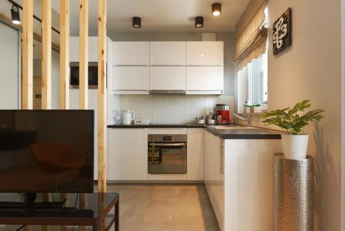 a kitchen with white cabinets and a table at Malta Apartament Parking by IMPERO in Poznań