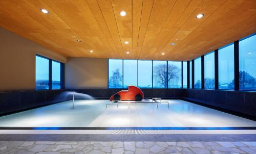 a swimming pool with a red chair in a room with windows at Apartments Heidenberger Delle Scuole in Colle Isarco