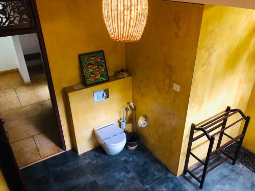 a bathroom with a toilet in a yellow wall at FireMoonGarden by Peacock Villa in Mirissa