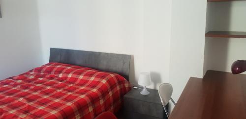 ein Schlafzimmer mit einem Bett mit einer roten karierten Decke in der Unterkunft HB via bono 57 in Bergamo
