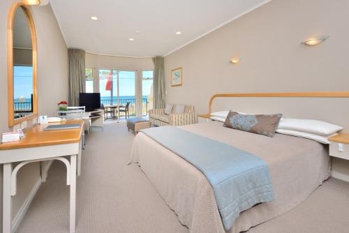 a hotel room with a large bed and a desk at Shoreline Motel in Napier