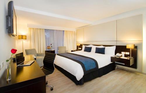 a hotel room with a large bed and a desk at Oro Verde Cuenca in Cuenca