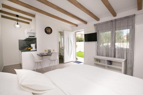 a white bedroom with a white bed and a table at Studio apartments Tara in Zadar