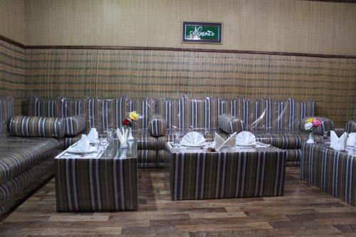a dining room with two tables and a couch at Daraysh Hotel in Sharjah