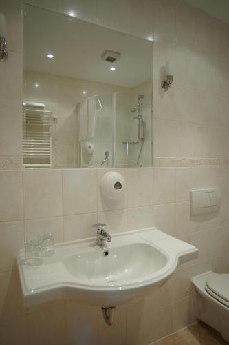 a bathroom with a sink and a mirror and a toilet at Hotel Grodzki in Poznań