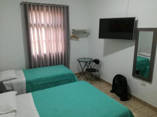 um quarto com duas camas e um espelho e uma televisão em Kayva em Trujillo