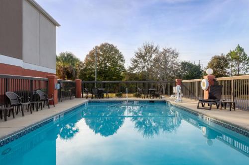 una piscina en un hotel con mesas y sillas en Holiday Inn Express & Suites Milton East I-10, an IHG Hotel, en Milton
