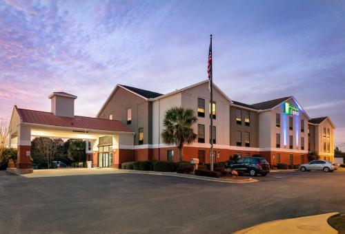 a hotel with an american flag in a parking lot at Holiday Inn Express & Suites Milton East I-10 by IHG in Milton