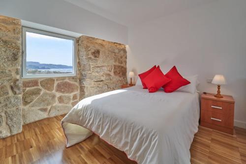 a bedroom with a stone wall and a bed with red pillows at Views and Beds in Pontevedra